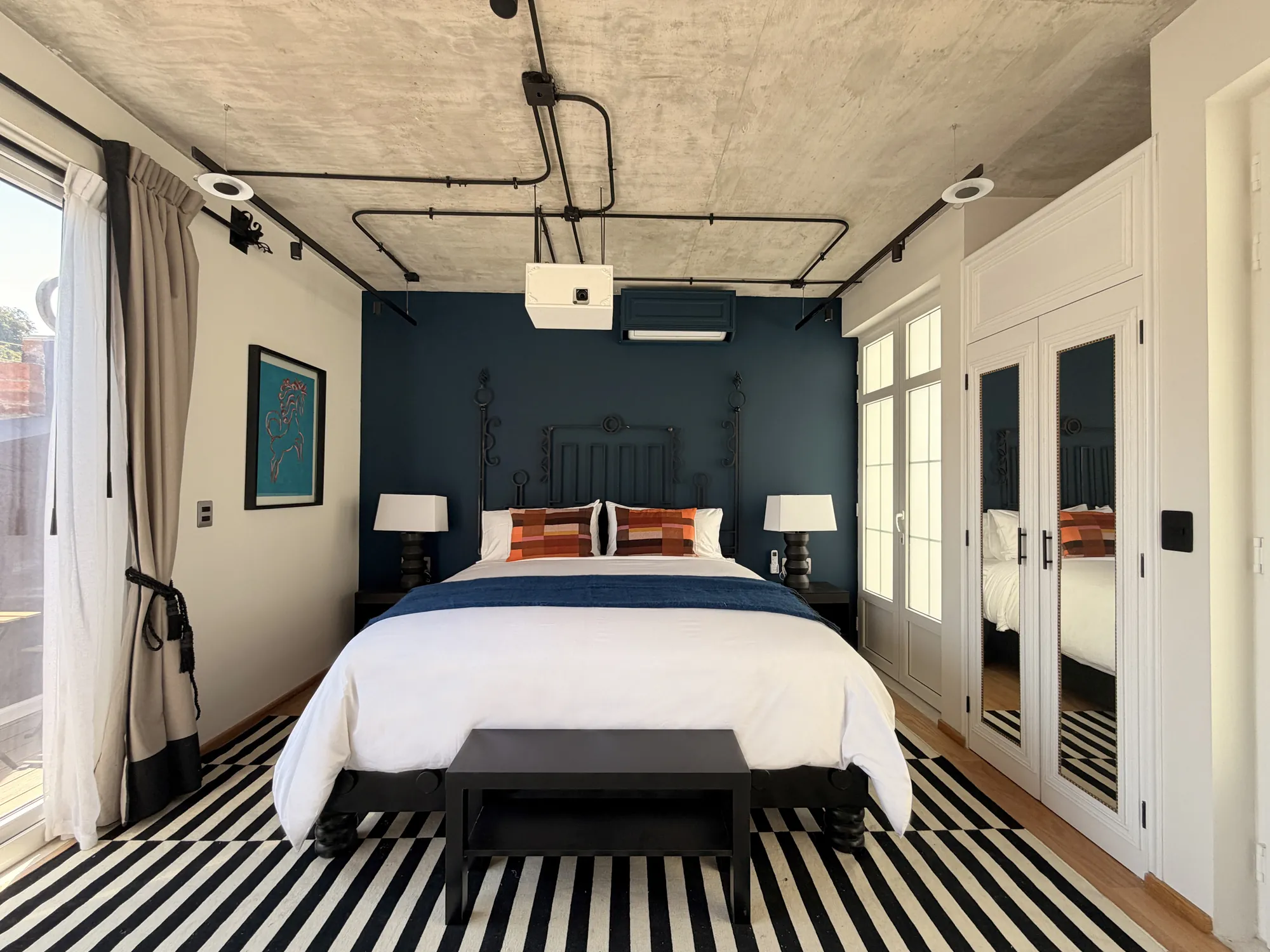 The King bed on a black-and-white striped rug, facing the balcony doors