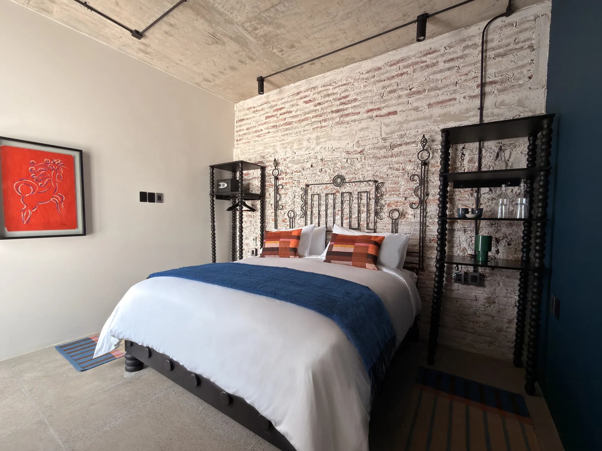 The room with the bed, a red painting on the wall and the black shelves