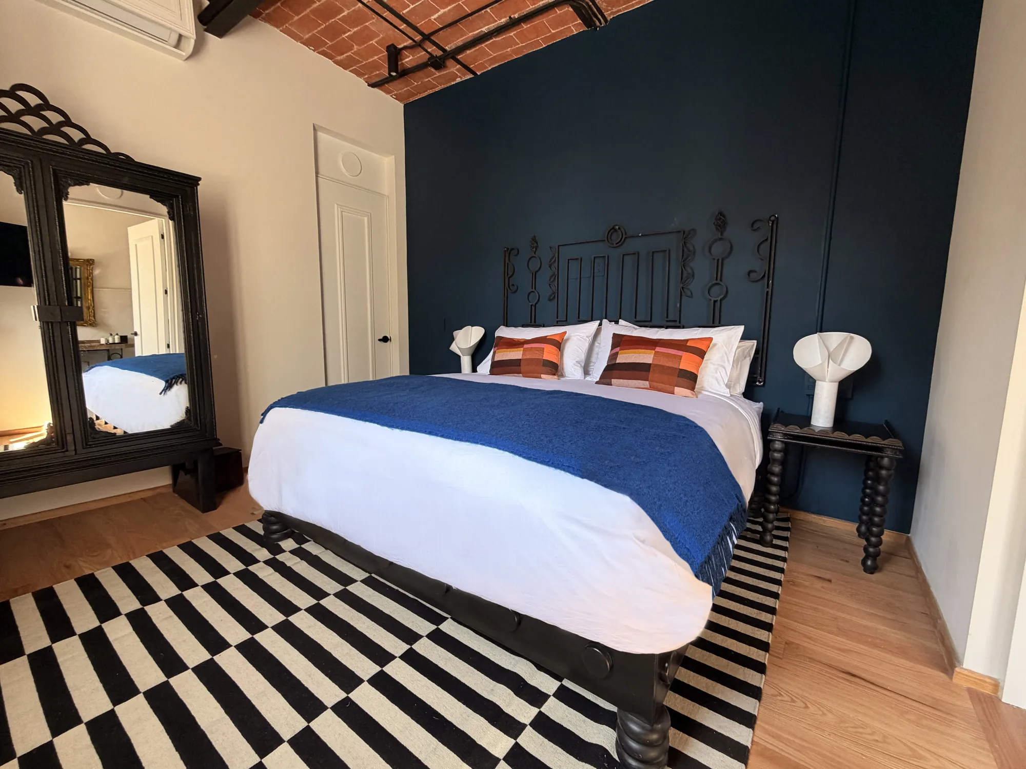 The bed under the brick ceiling, with a wardrobe with a mirror to one side