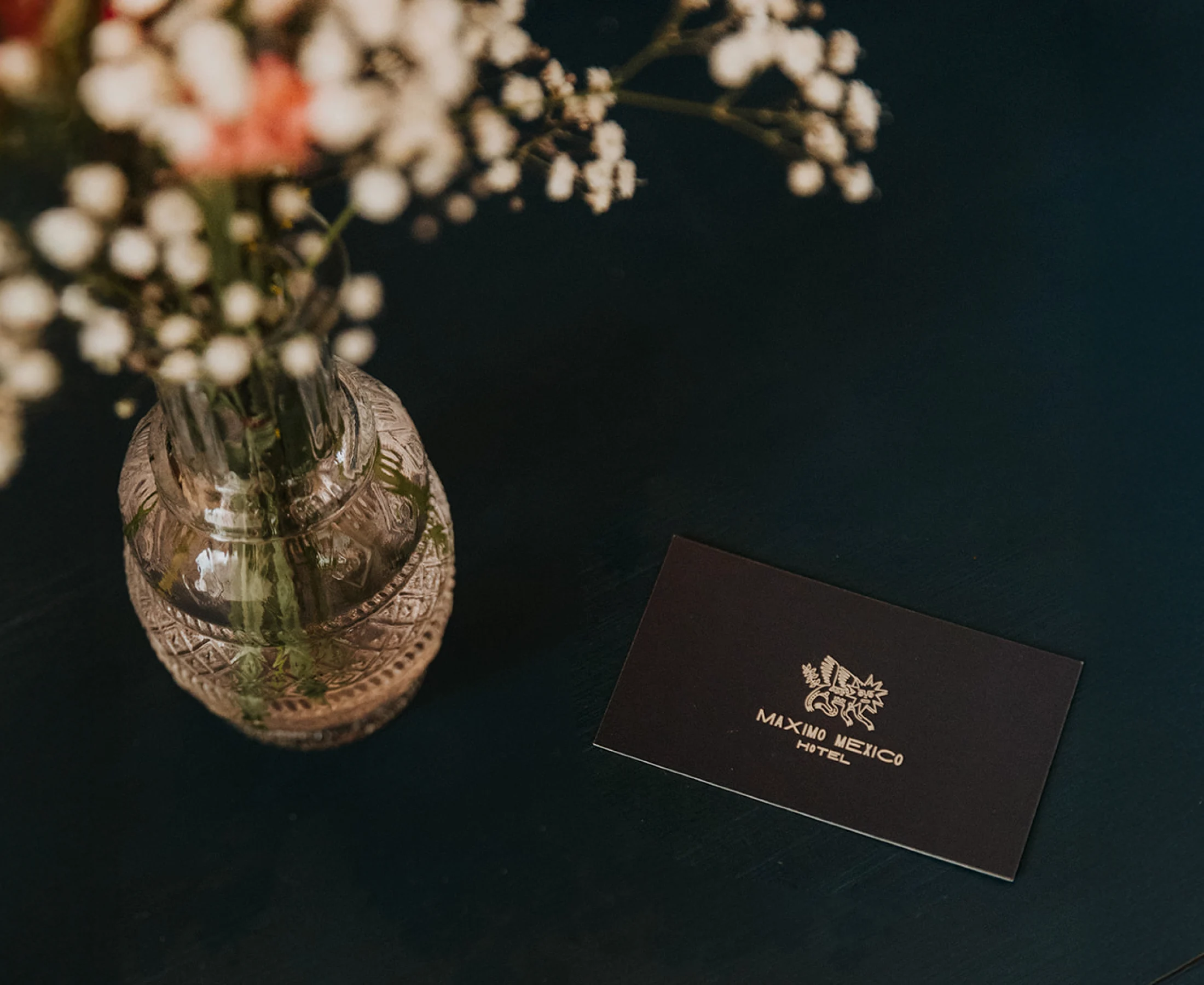 A hotel card on a dark table, with a vase of colourful flowers