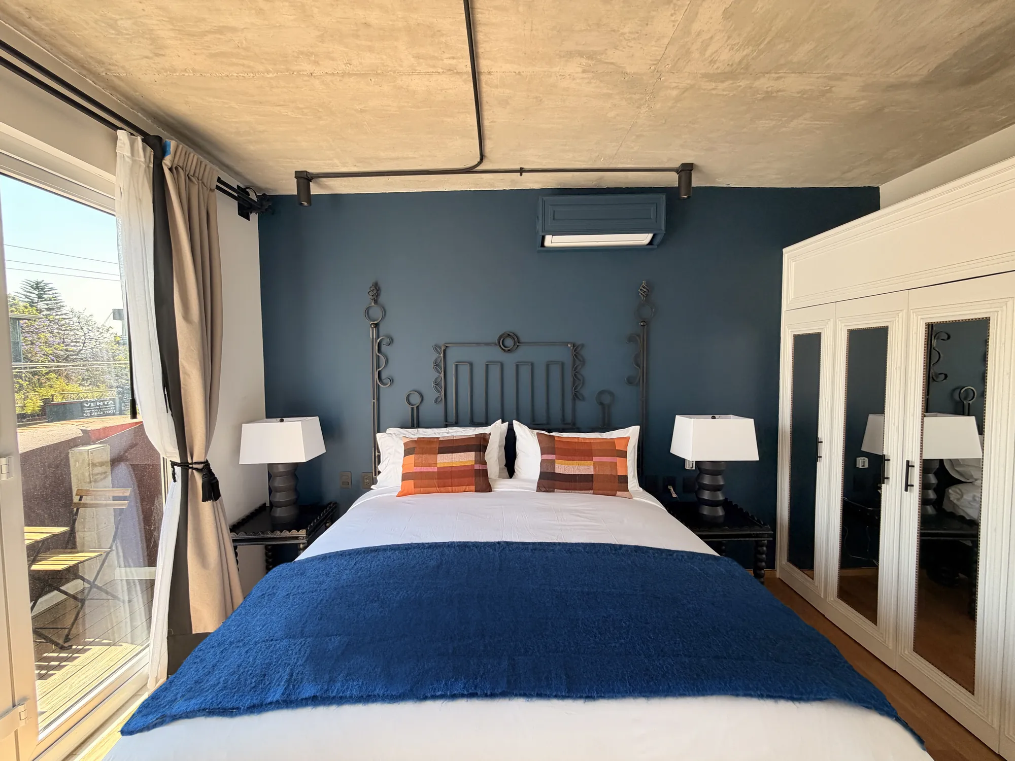 The bed with the balcony door and the closet with mirrors