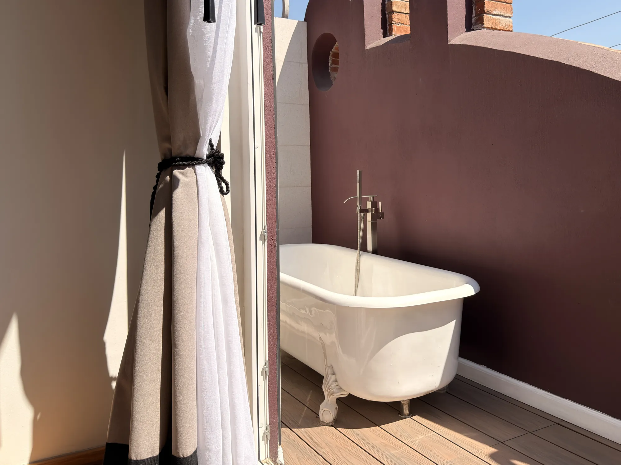 The outdoor clawfoot tub on the balcony, beside the curtain