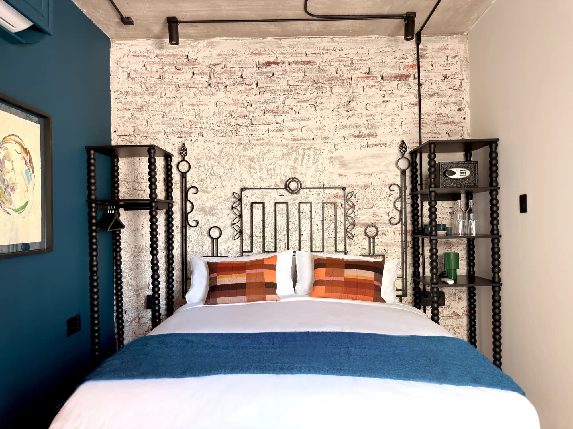 The King bed seen head-on, under the wrought-iron headboard, with colourful cushions and a blue blanket