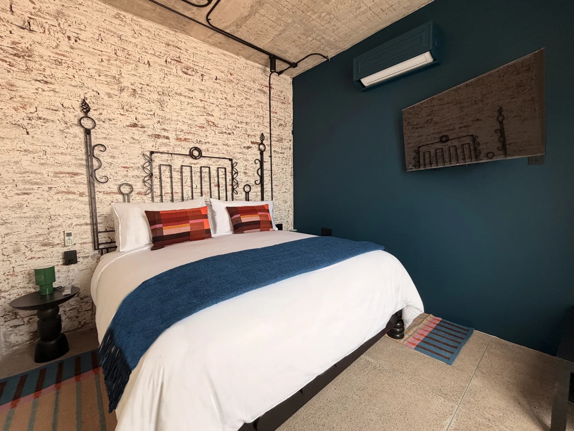 The King bed beside the blue wall with the TV and the air conditioning