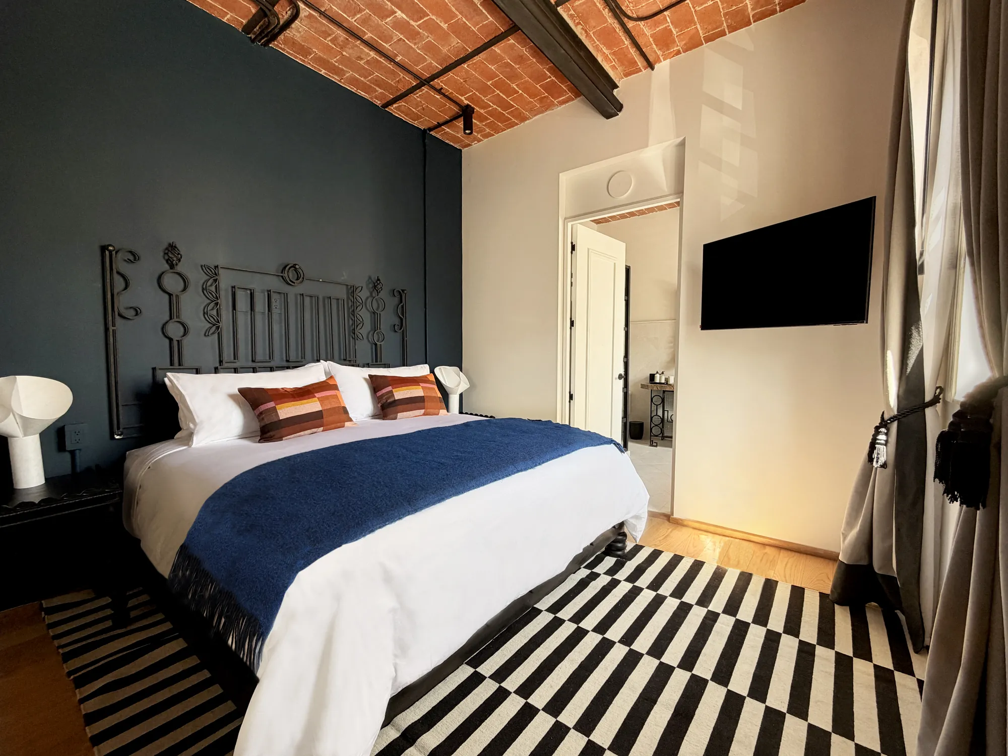 The King bed with a striped rug and the brick ceiling with beams